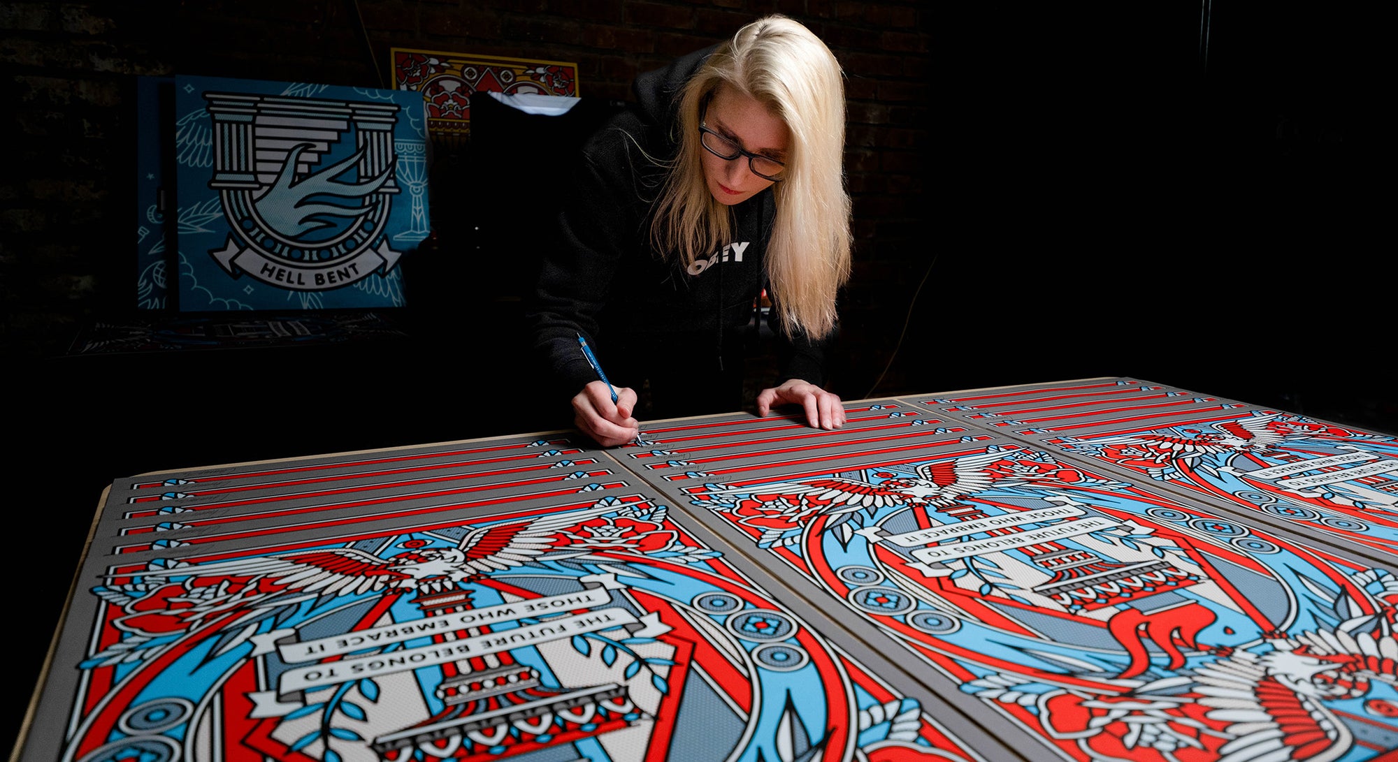 Lisa Champ of Red Halftone signing large limited edition prints on a table in her studio