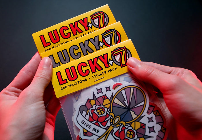Hands holding a 'Lucky 7' sticker pack with colorful designs on a dark background