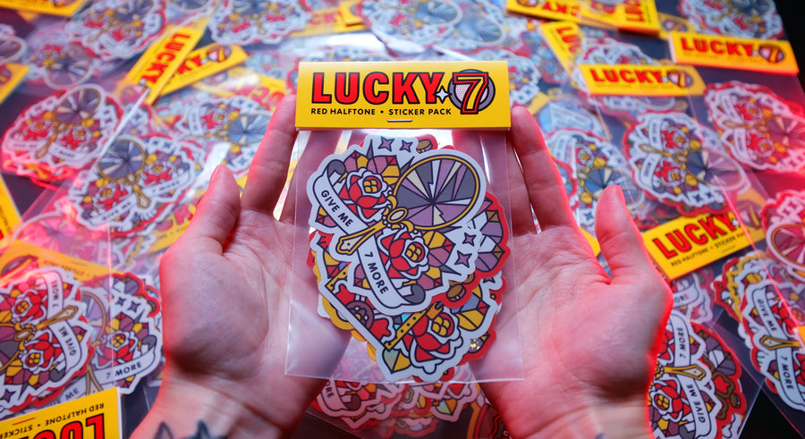 Hands holding a 'Lucky 7' sticker pack by Red Halftone with colorful sticker designs against a background of similar packs.