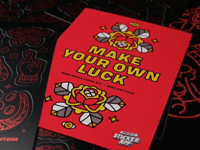 A close up of a back design of a sticker sheet with text "Make your own luck" and floral illustrations on a red background