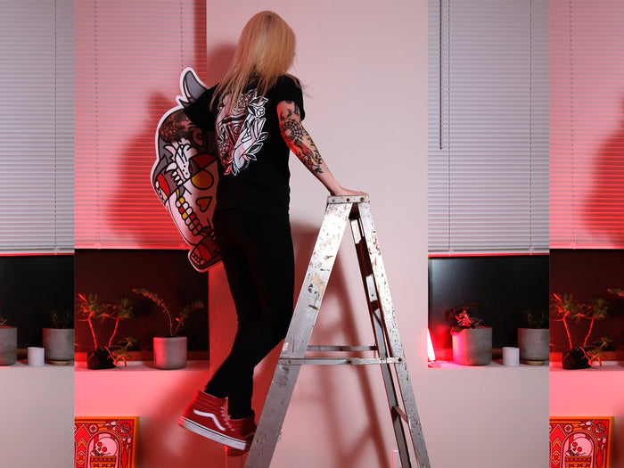Red Halftone holding a wall graphic while on a ladder in a room with red lighting