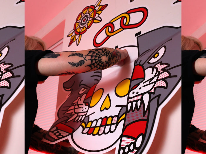 Red Halftone applying a colorful tattoo-inspired wall graphic to a white wall.