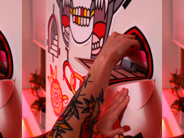 Red Halftone applying a colorful tattoo-inspired wall graphic to a white wall.