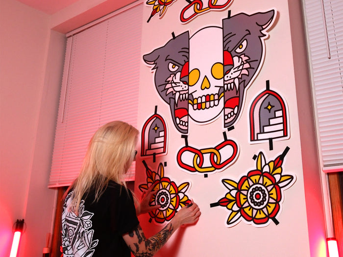 Red Halftone applying a colorful tattoo-inspired wall graphic to a white wall.