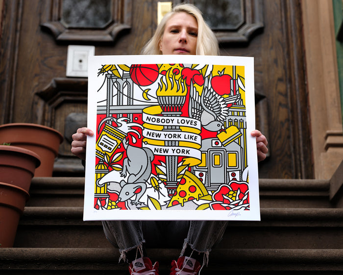 The artist Red Halftone holding a colorful limited edition screen print with New York-themed design against a on a stoop.