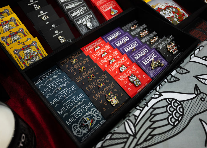 Collection of Red Halftone enamel pins in a display case with various designs.
