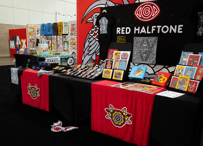 Red Halftone booth with various items on a table at Adobe MAX