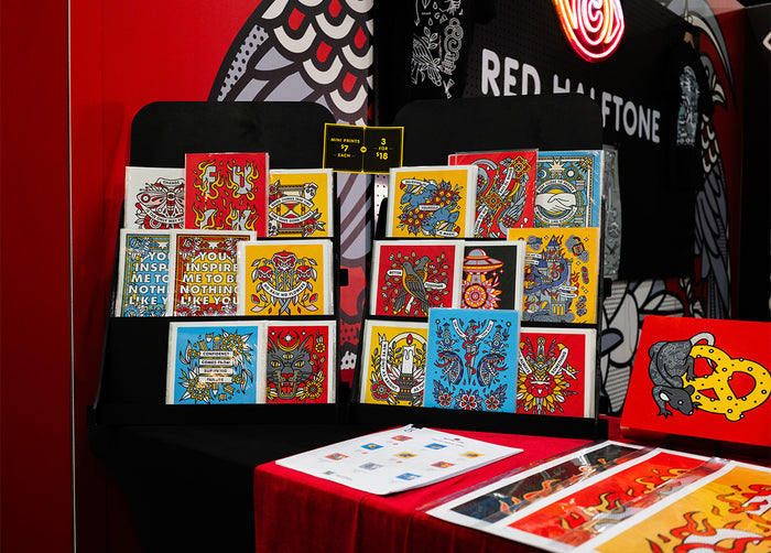 Collection of colorful Red Halftone mini prints displayed on a stand at Adobe MAX