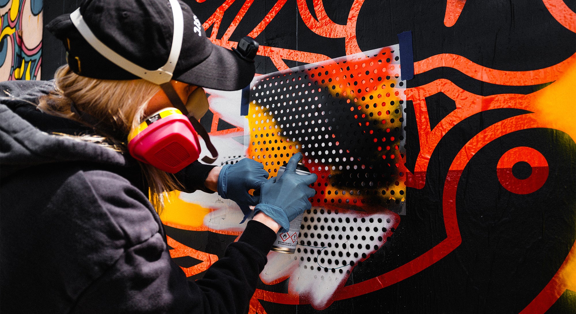 Artist Red Halftone using a stencil to paint a halftone pattern