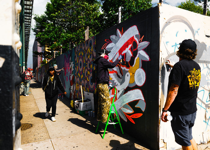 Street artists spray painting at East New York Walls