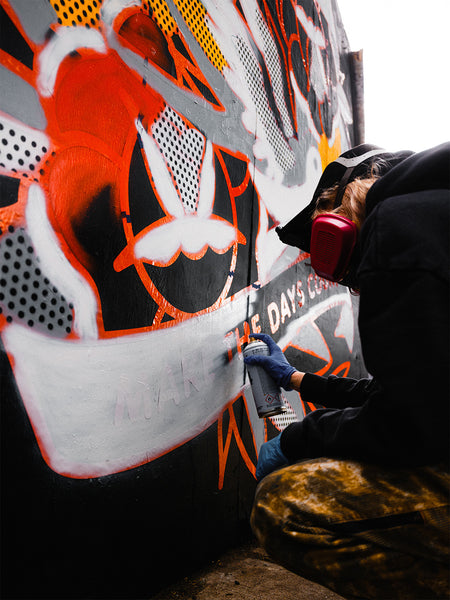 Artist Red Halftone painting a mural at East New York Walls