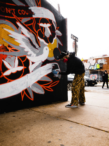 Artist Red Halftone painting a mural at East New York Walls