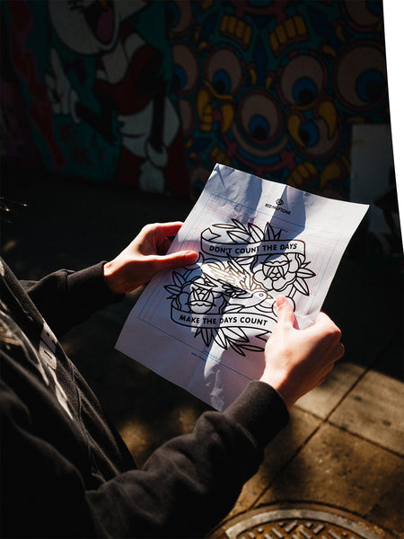 Artist holding a paper with a line drawing with measurements of the art for a mural