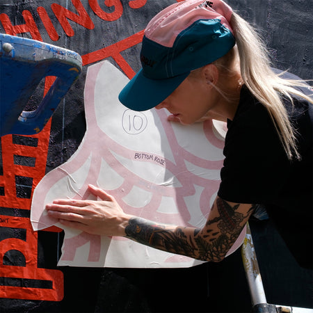 Lisa Champ of Red Halftone applying orange vinyl to a wall.