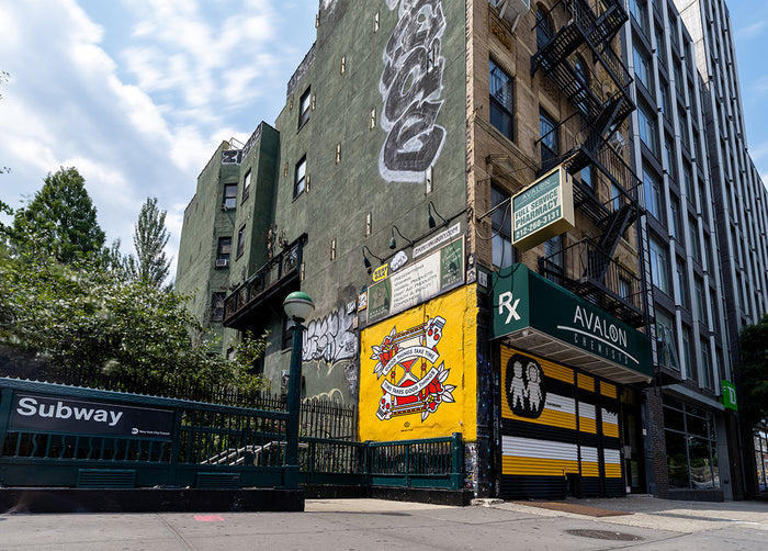 A mural by the artist Red Halftone on a building exterior outside of the subway in New York City. The design is of an hourglass surrounded by roses and skulls with the text "Good things take time, time takes good things".