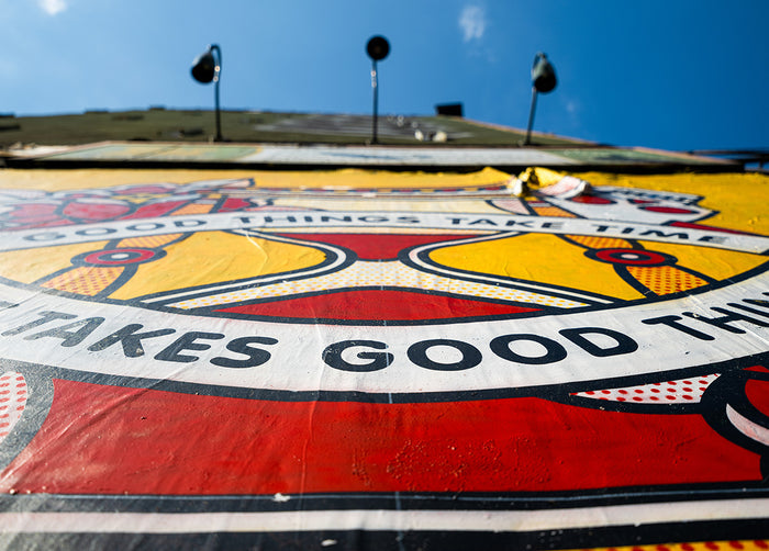 A close up of a mural by the artist Red Halftone showing the texture of the wall with red, yellow, white and black colors.