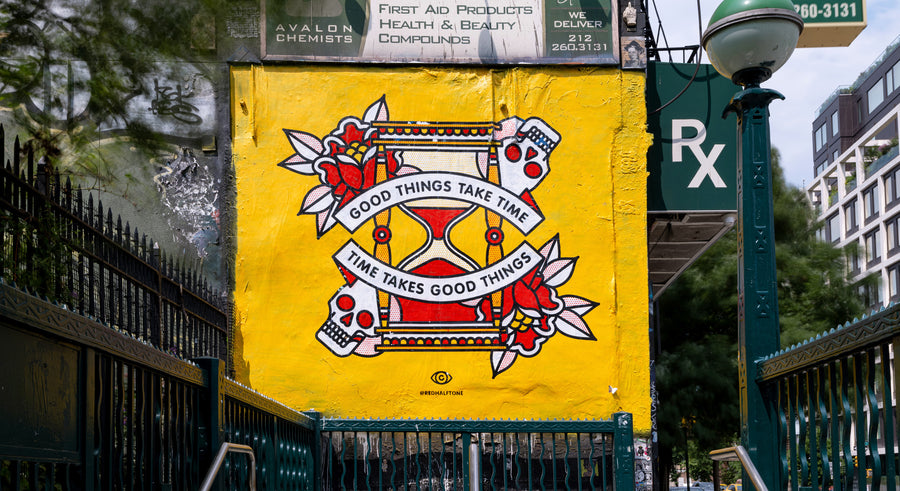 A mural by the artist Red Halftone on a building exterior in the Lower East Side of New York City. The design is of an hourglass surrounded by roses and skulls with the text "Good things take time, time takes good things".
