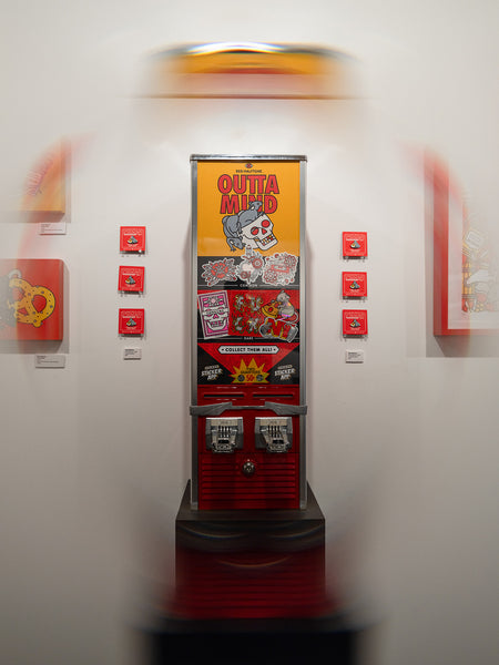 Vintage sticker vending machine with colorful Red Halftone-branded graphics on a white wall.