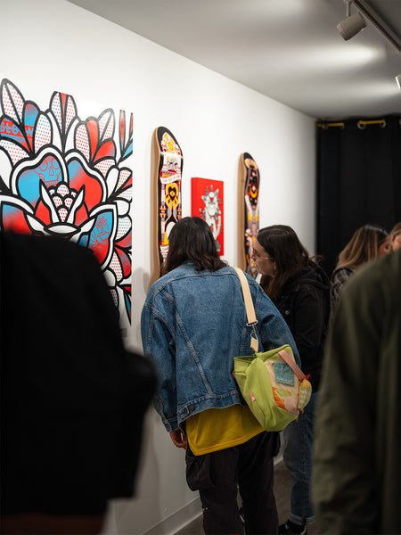 People observing Red Halftone art on skateboards displayed on a wall at Studio6 Gallery