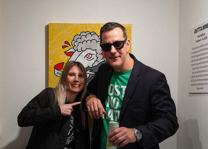 Two people posing in front of a colorful painting of a sheep by Red Halftone