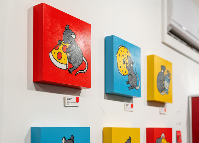 Set of red, yellow and cyan paintings by Red Halftone on a white wall.