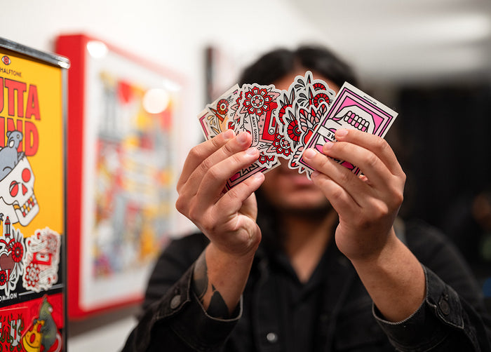Person holding Red Halftone Stickers in front of their face with a colorful background