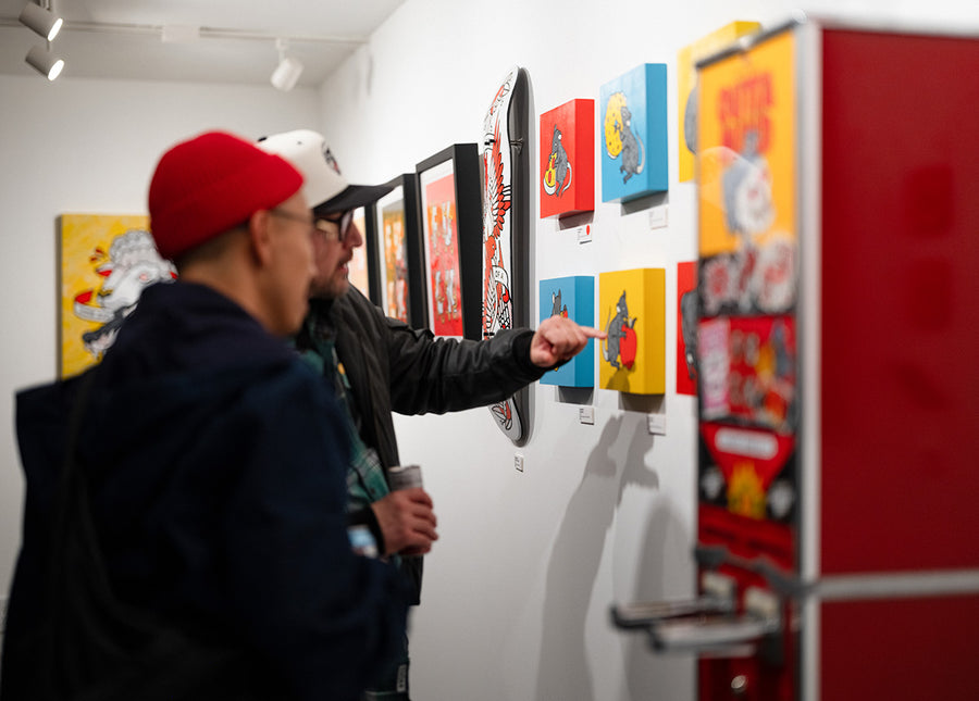 Two people looking at colorful artwork by Red Halftone on a wall at Studio6 Gallery.