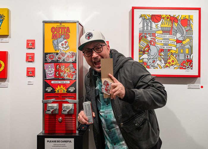 Person posing with stickers next to a vintage Red Halftone-branded sticker vending machine.
