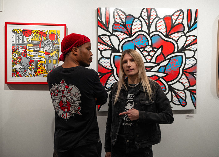 Red Halftone and a fan standing in front of artwork on the wall at Studio6 Gallery.