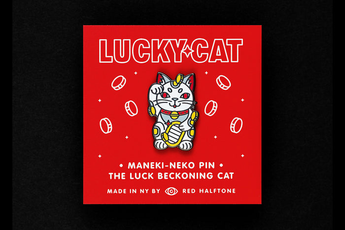 Maneki-neko enamel pin on a red background with coins and text that reads "Lucky Cat"
