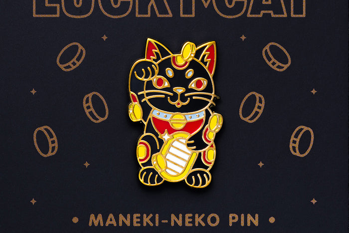 Maneki-neko enamel pin on a dark background with coins and text