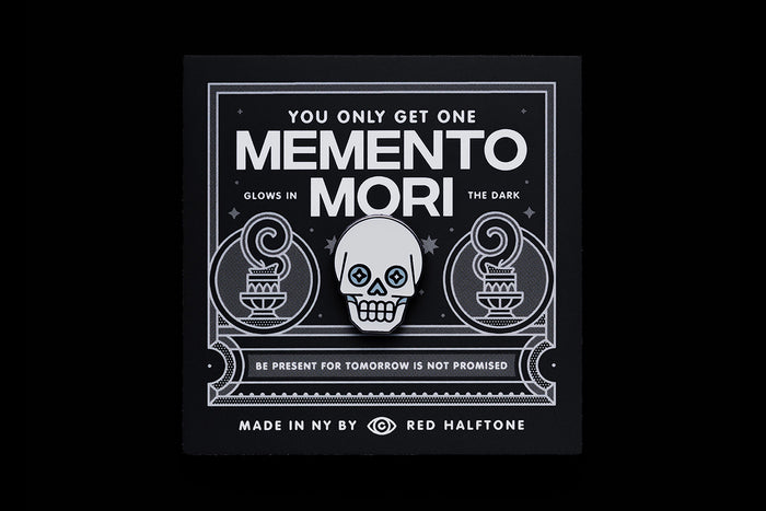 Skull enamel pin on a black card with text that reads "You Only Get One Memento Mori"