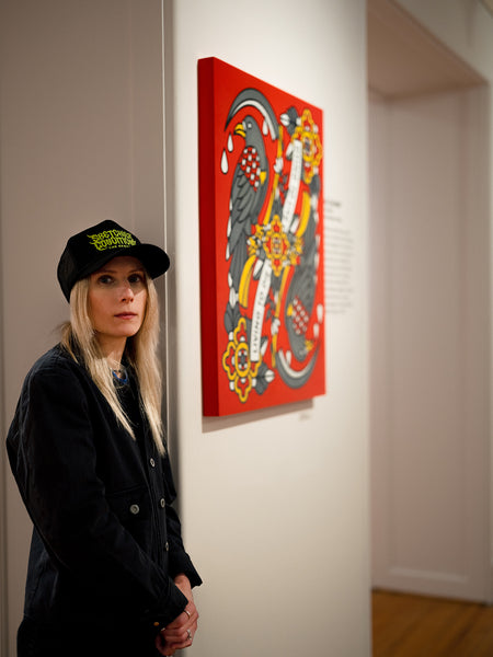 Lisa Champ of Red Halftone standing next to her colorful artwork on a wall