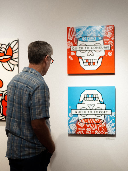 Man looking at artwork by Red Halftone on a wall with a skull design and text.