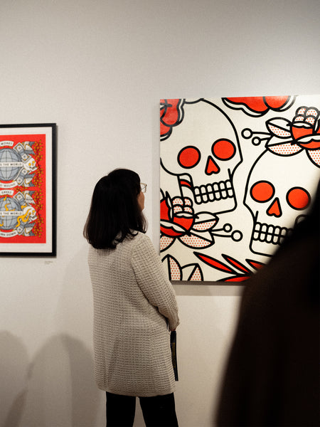 Person looking at a painting by Red Halftone with a skull design in an exhibition setting.