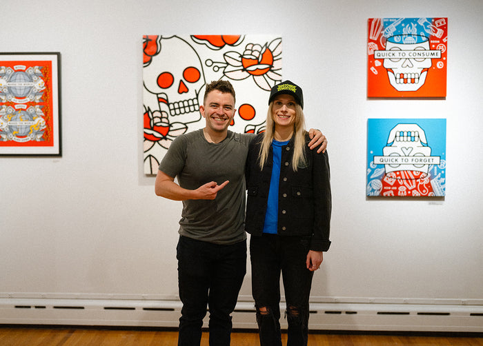 Lisa Champ and another person standing in front of her artwork on the wall.