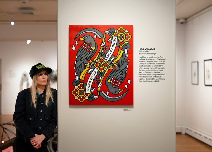 Lisa Champ of Red Halftone standing next to a piece of her artwork on a wall in an art gallery.