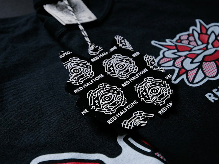 The back of a hang tag design with black and white graphics against a black t-shirt with red and white graphics