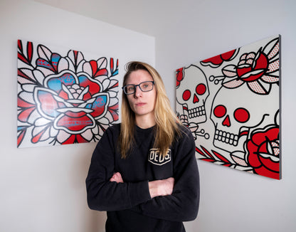 Lisa Champ, also known as the artist, Red Halftone standing in front of two of her large paintings hung on the wall behind her.
