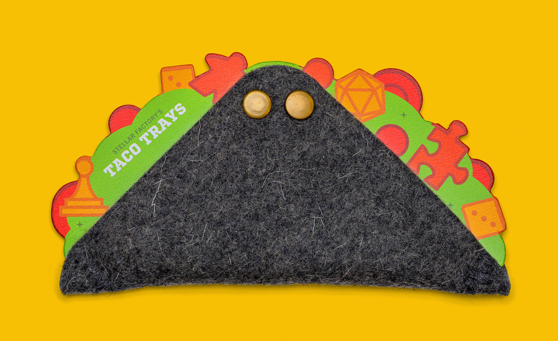 The front side of the taco tray product and packaging featuring colorful game pieces arranged on a taco shell.