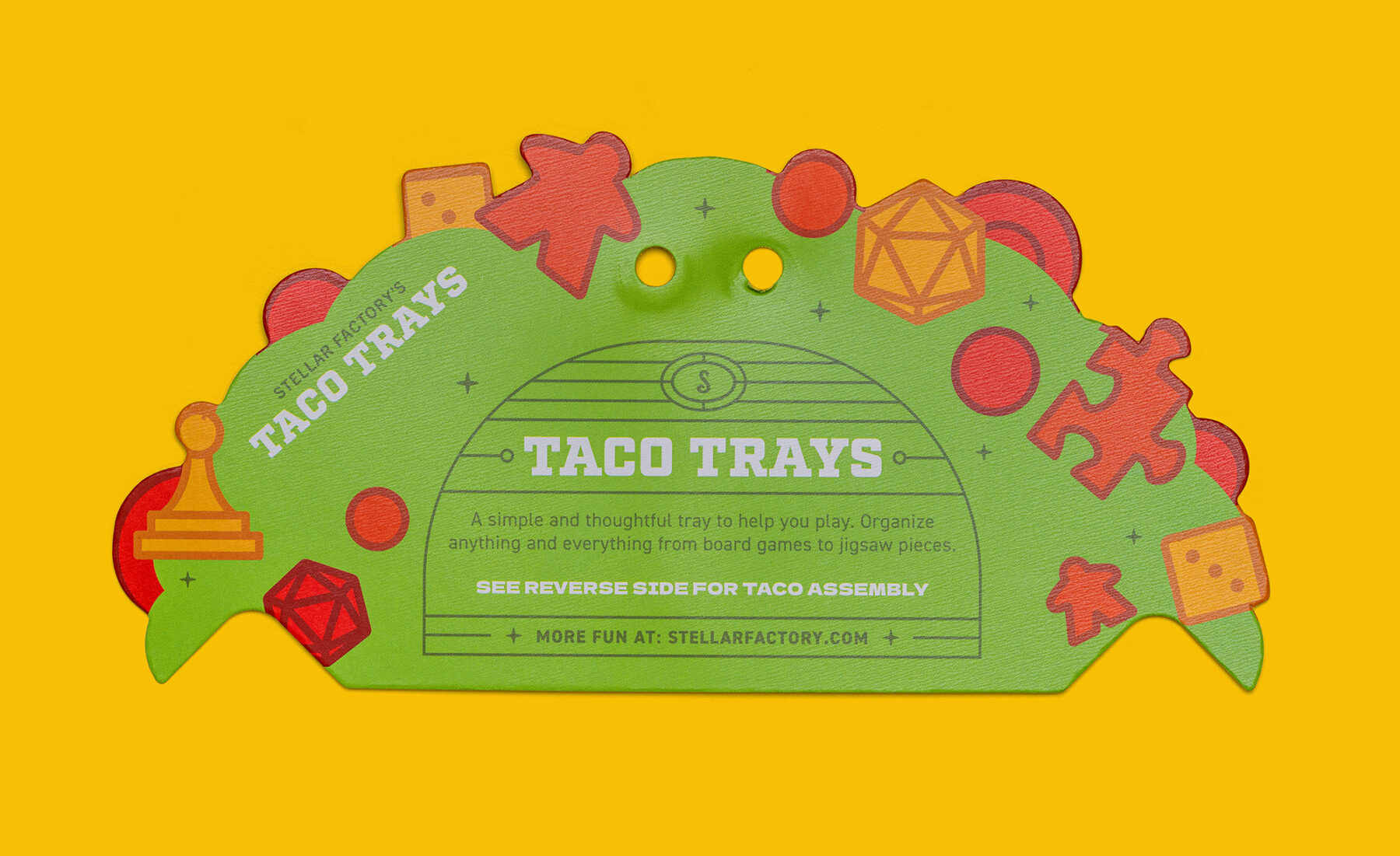 An isolated view of the front side of the packaging. It features colorful game pieces arranged on a taco shell. The center part reveals copy about the product and Stellar Factory.